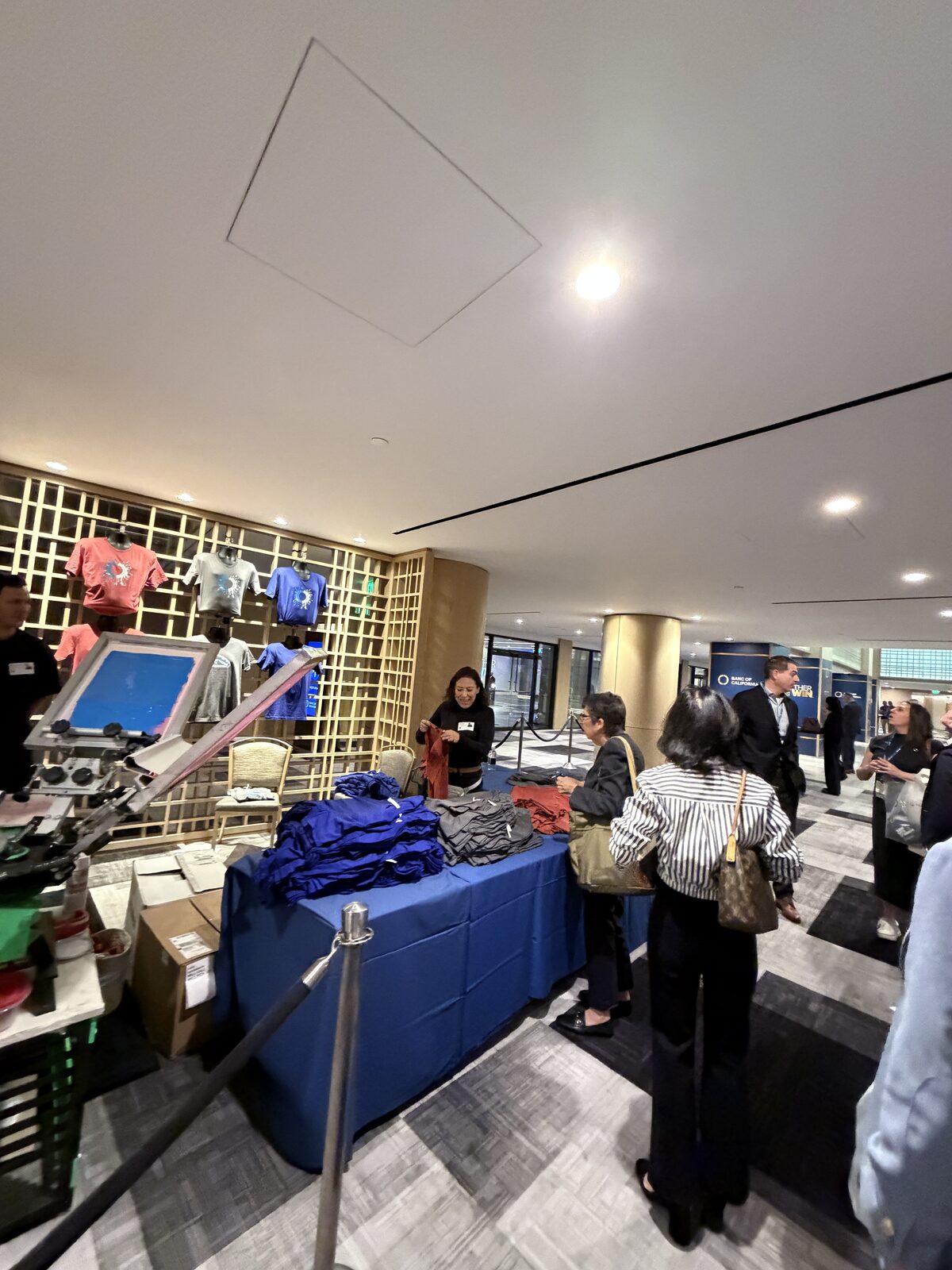 Staff handing a freshly printed shirt to a guest at a summit t-shirt bar